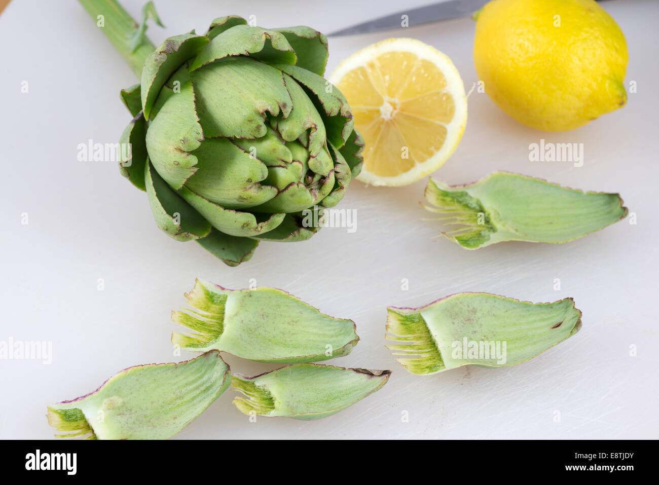 Entfernen die äußeren Blätter aus frisch gepflückten Artischocken kochen bereiten. Stockfoto