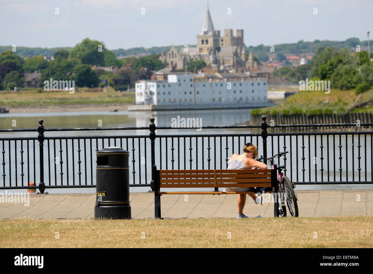 Chatham, Kent, England, UK. Rochester Kathedrale von Chatham - Frau auf eine Bank und ihr Fahrrad gesehen Stockfoto