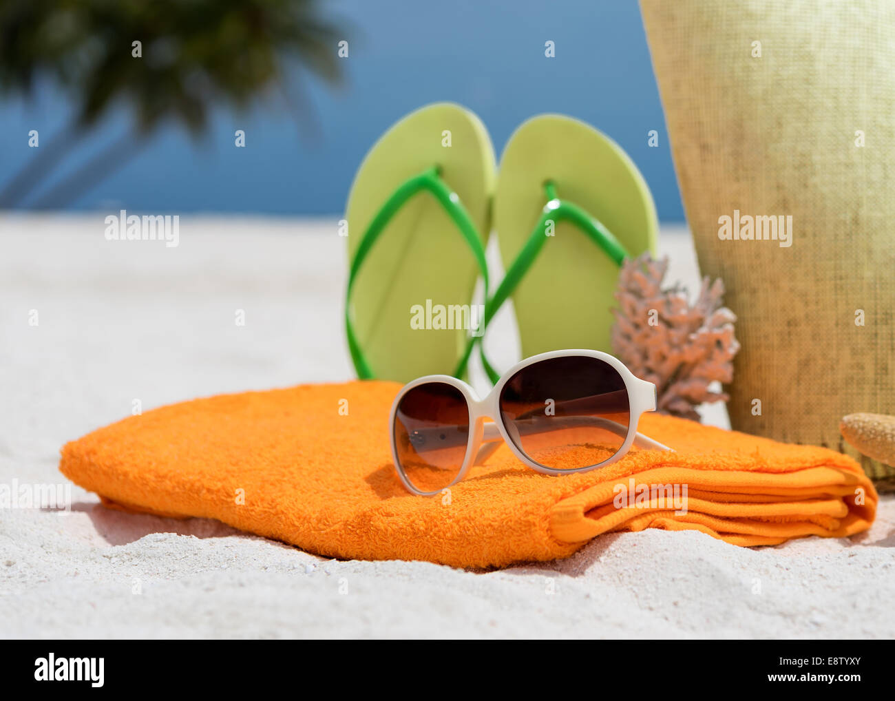 Sommer-Strand-Tasche mit Seestern, Handtuch, Burschen gesungen und Flip-Flops am Sandstrand Stockfoto