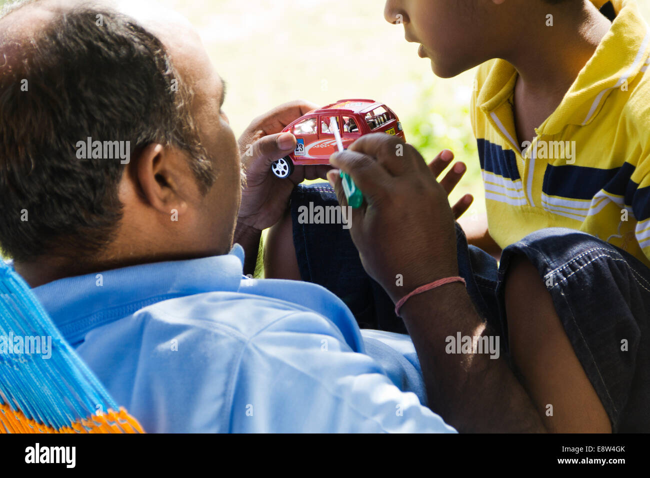 1 indischer Mann Reparatur Auto-Spielzeug mit Kind Stockfoto
