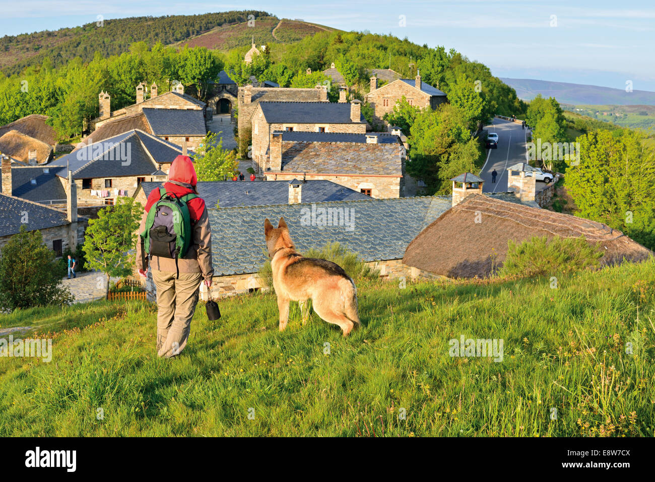 Spanien, Jakobsweg: Pilger mit deutscher Schäferhund auf einer Anhöhe über mittelalterliche Dorf O Cebreiro Stockfoto