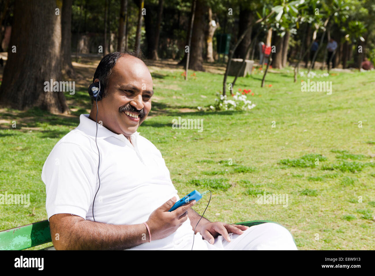 1 indischer Mann hören von Musik im Park Stockfoto