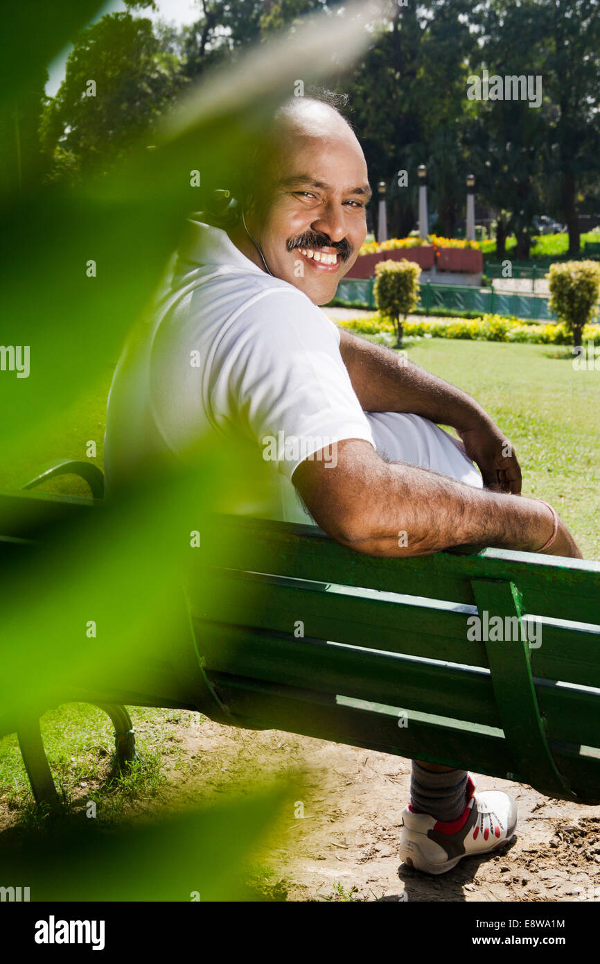 1 indischer Mann hören von Musik im Park Stockfoto