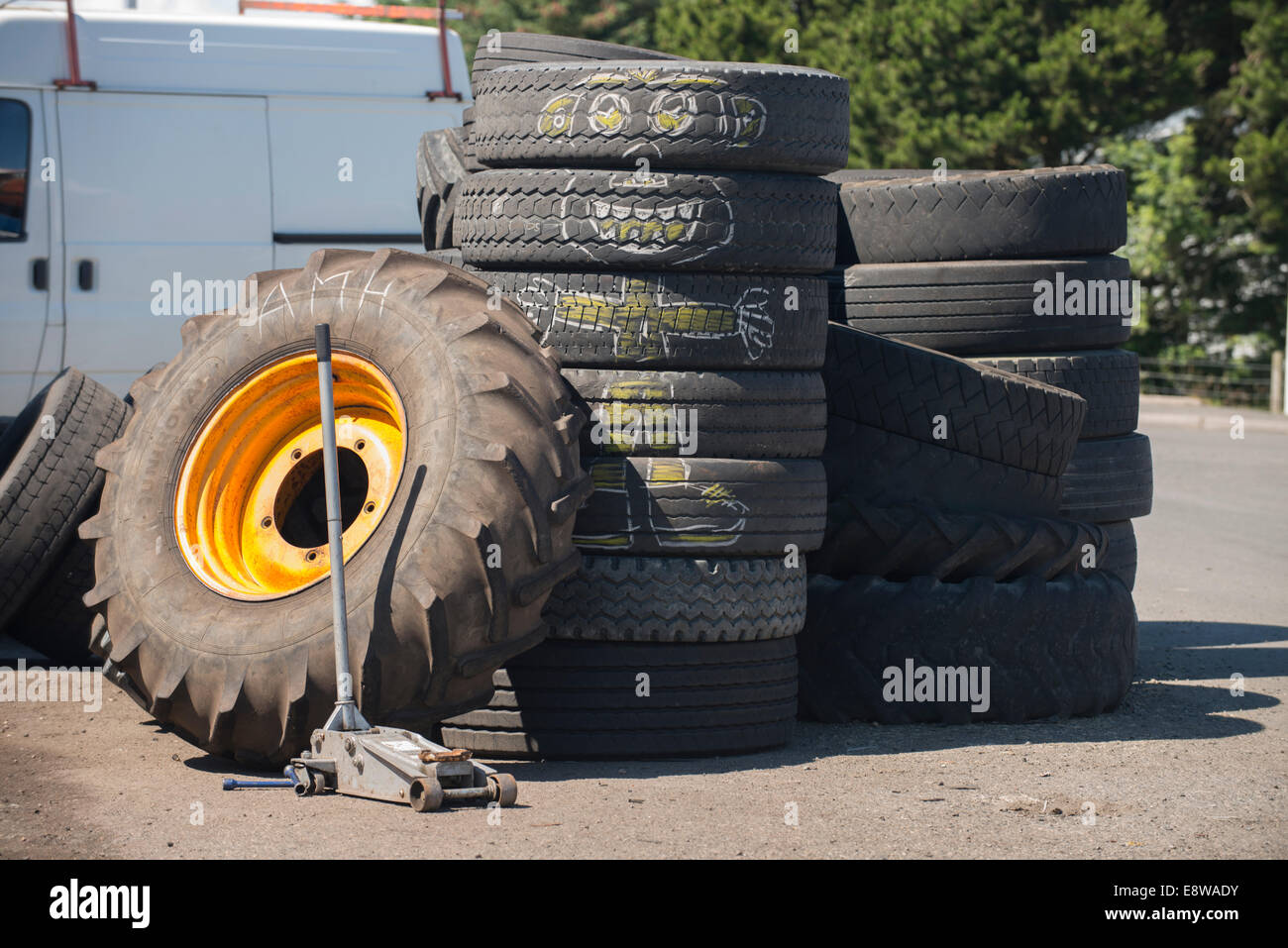 Alte Autoreifen und ein Traktor Rad gestapelt vor eine Garage, eine Kreidezeichnung Cartoon-Charakter erscheint auf den alten Reifen Stockfoto