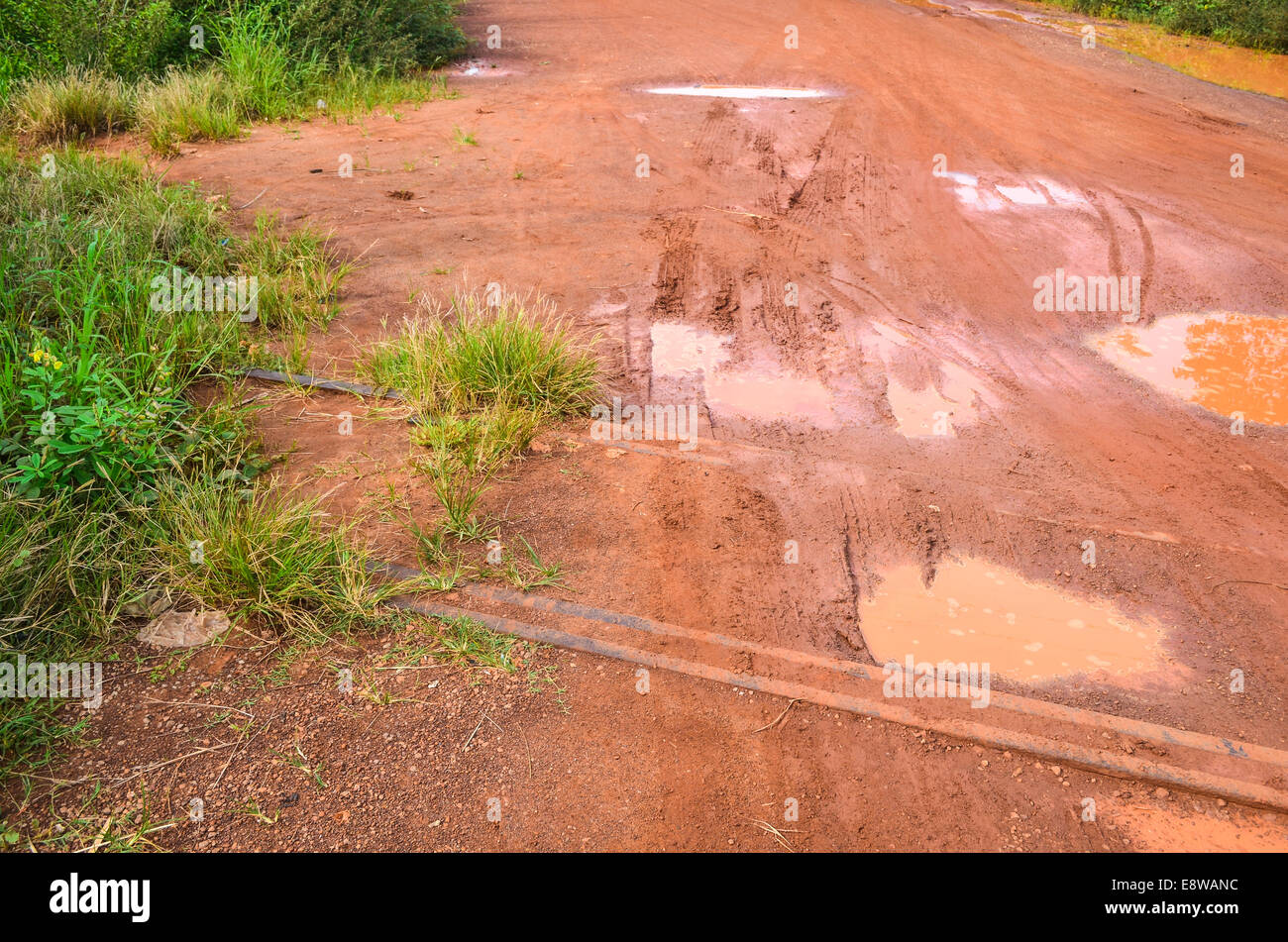 Schlammige Feldwege in Nigeria während der Regenzeit und eine verlassene alte Bahnstrecke die überfluteten Pfützen Stockfoto
