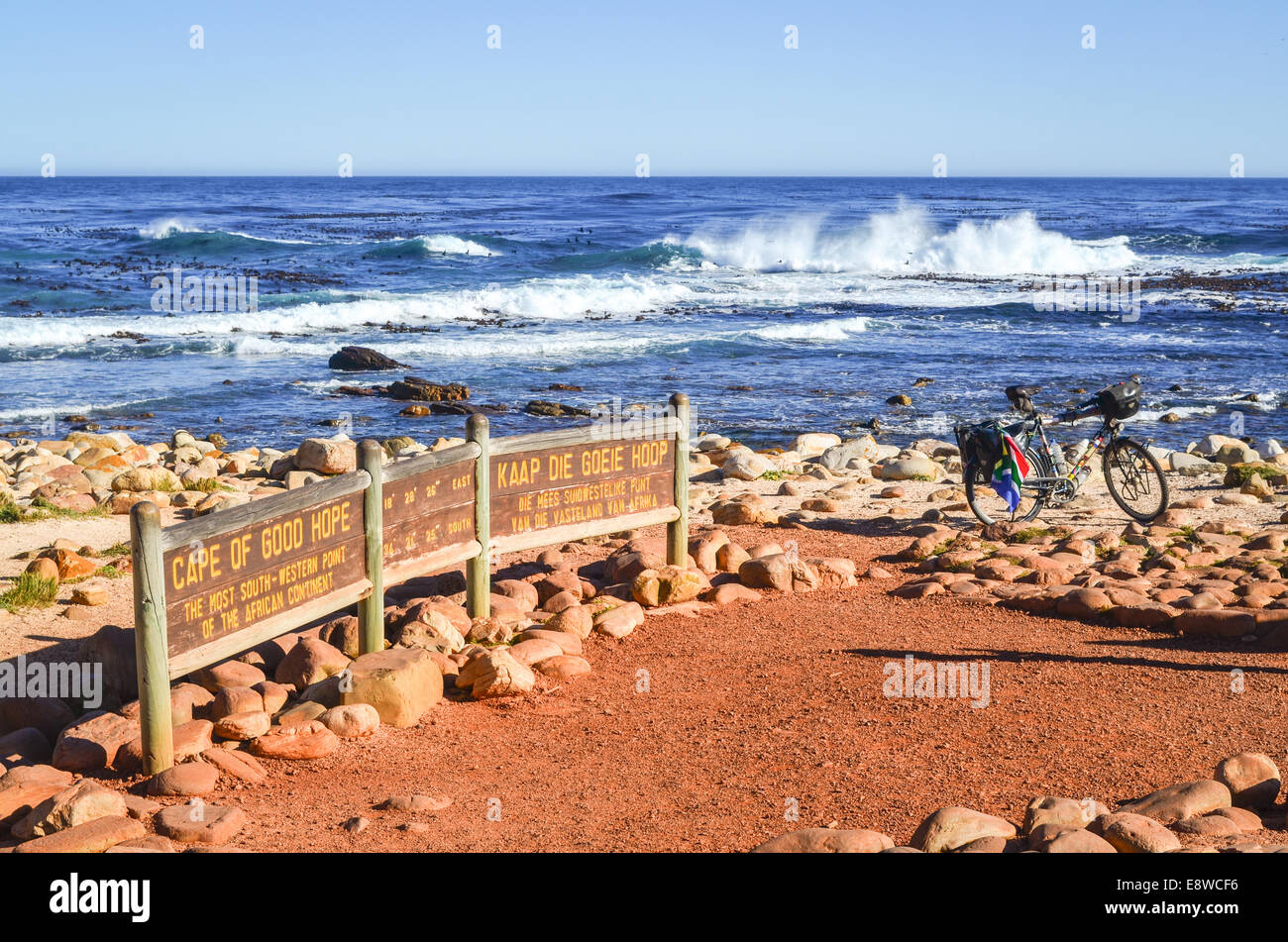 Zeichen für das Kap der guten Hoffnung an der südwestlichste Spitze Afrikas und ein Tourenrad vor den Wellen Stockfoto