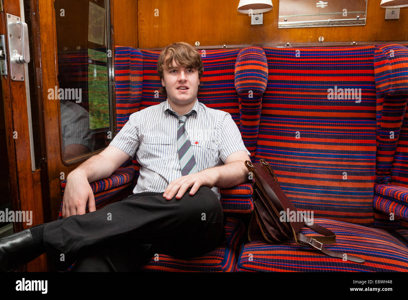 Ein junger Freiwilliger Eisenbahnarbeiter (Kontrolleur) sitzen in einem Waggon vom Nottingham Transport Heritage Centre, England, UK. Stockfoto