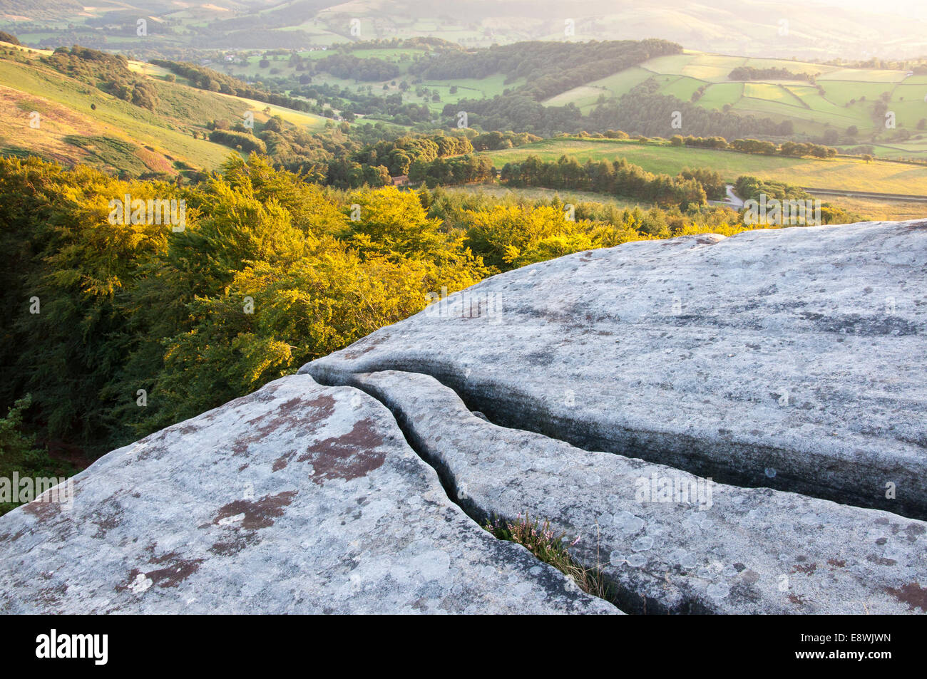 Risse im Felsen auf Stanage Edge mit Blick über sonnenbeschienene Sommerlandschaft Stockfoto