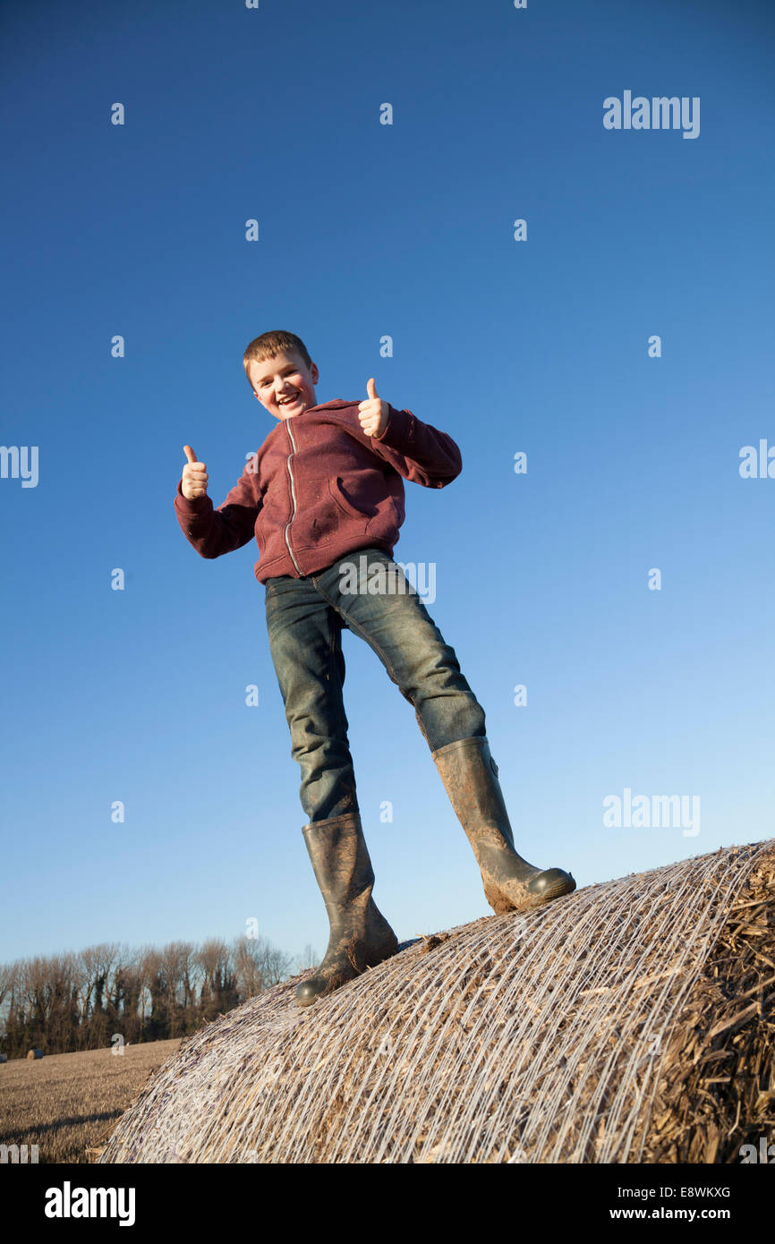 Lächelnd Bauernjunge auf einem Strohballen Stockfoto