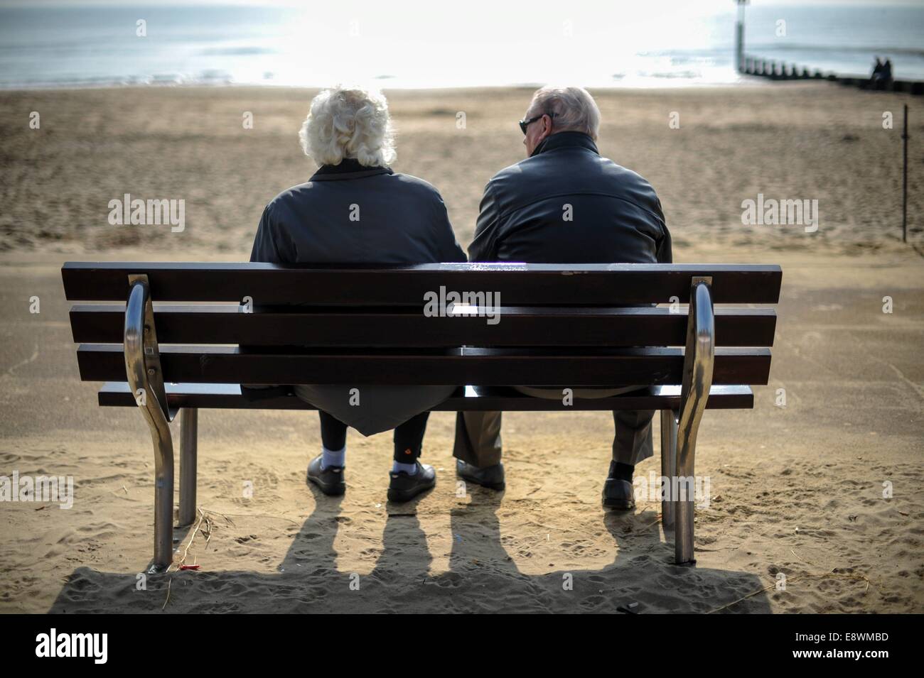 n älteres Ehepaar gelten entspannen, in der Sonne auf einer Bank am Meer in Bournemouth Stockfoto