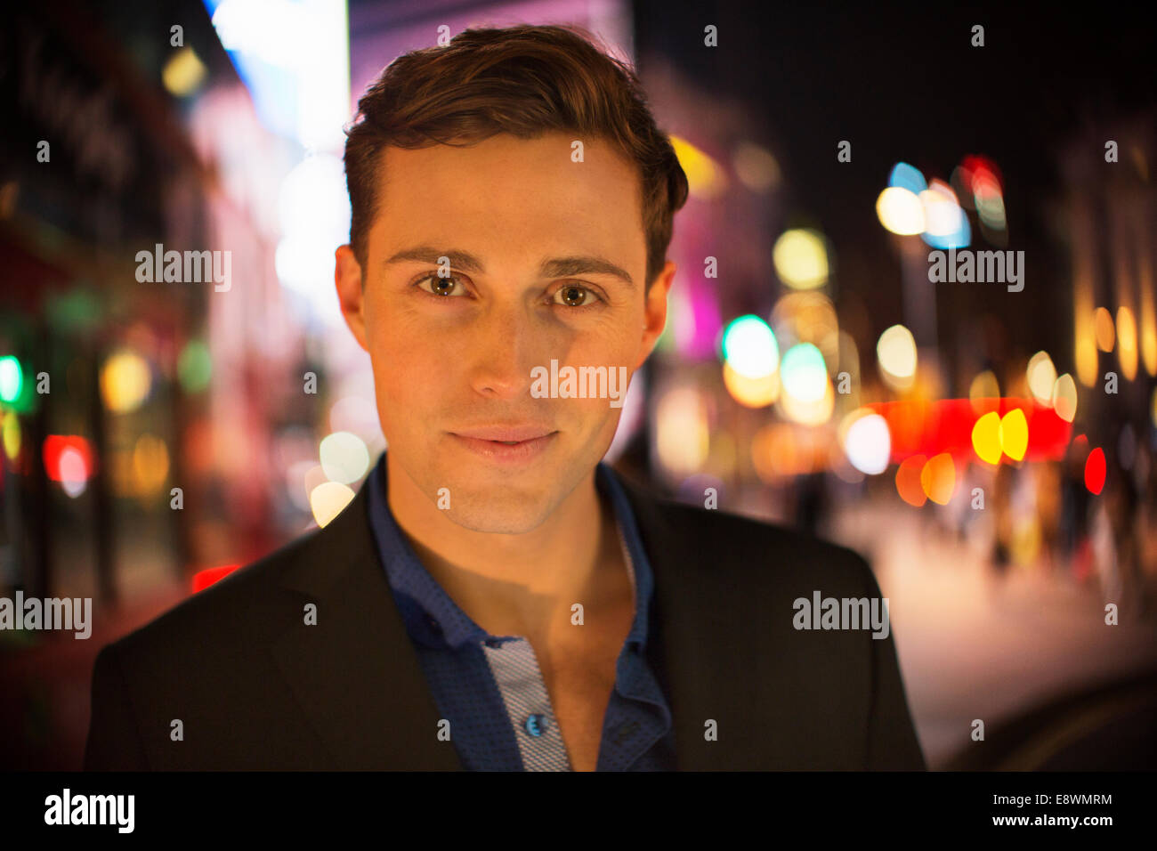Mann lächelnd auf Stadtstraße in der Nacht Stockfoto