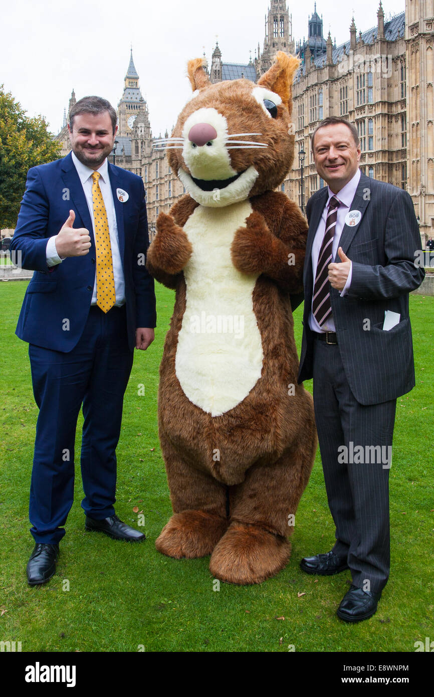 London, UK. 15. Oktober 2014. Natur-Aktivisten, begleitet von einer riesigen roten Eichhörnchen, Bob, fordere MPs 'Abstimmung für Bob' bei einem Fototermin vor dem Parlament. Ihr Ziel ist zu MPs, Natur in Großbritannien zu unterstützen. Bild: MPs Andrew Stephenson, links, und Jason McCartney posieren mit Bob das rote Eichhörnchen. Bildnachweis: Paul Davey/Alamy Live-Nachrichten Stockfoto