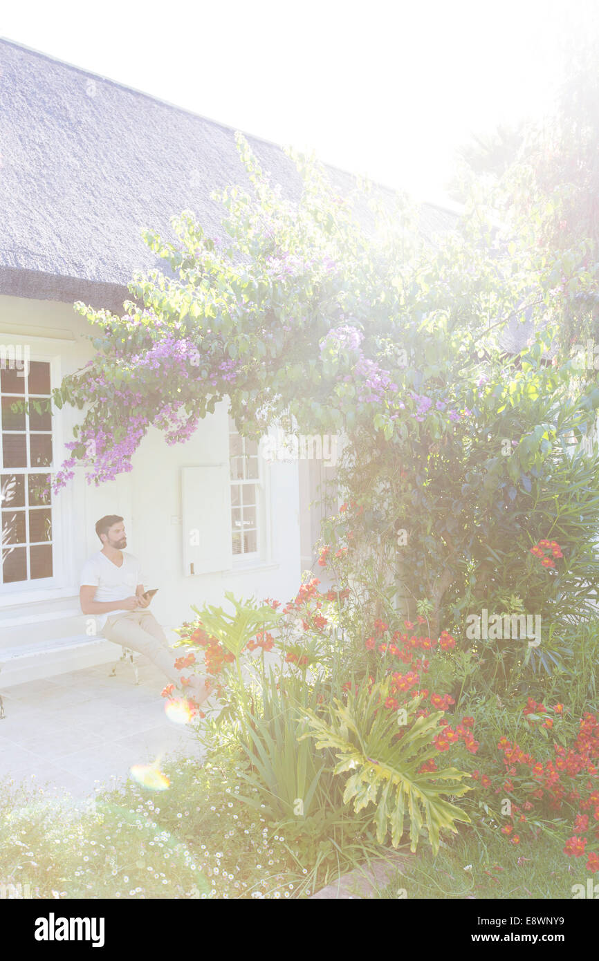 Mann auf der Veranda, die Blumen im Garten zu bewundern Stockfoto
