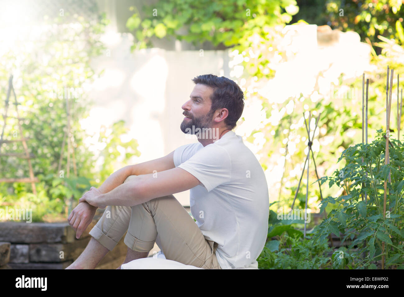 Lächelnder Mann entspannend im Hinterhof Stockfoto