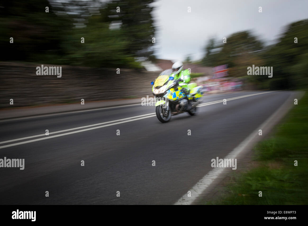 Polizei-Motorradfahrer beschleunigt vorbei Zuschauer wehende Union Fahnen in Bereitschaft für die Tour of Britain 2014-Radrennen. Stockfoto