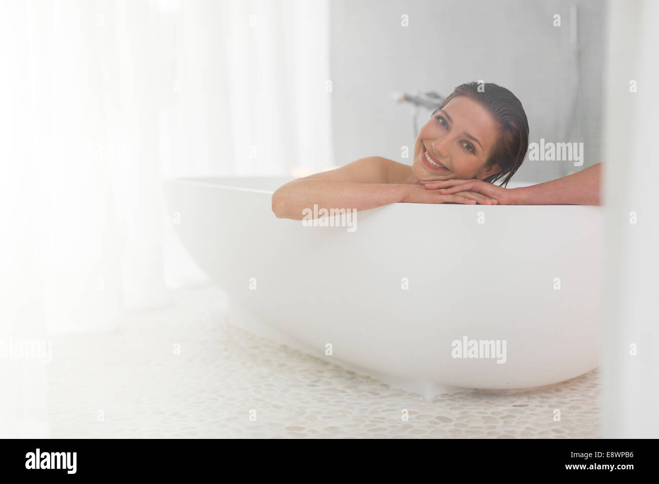 Lächelnde Frau unter Bad im modernen Badezimmer Stockfoto