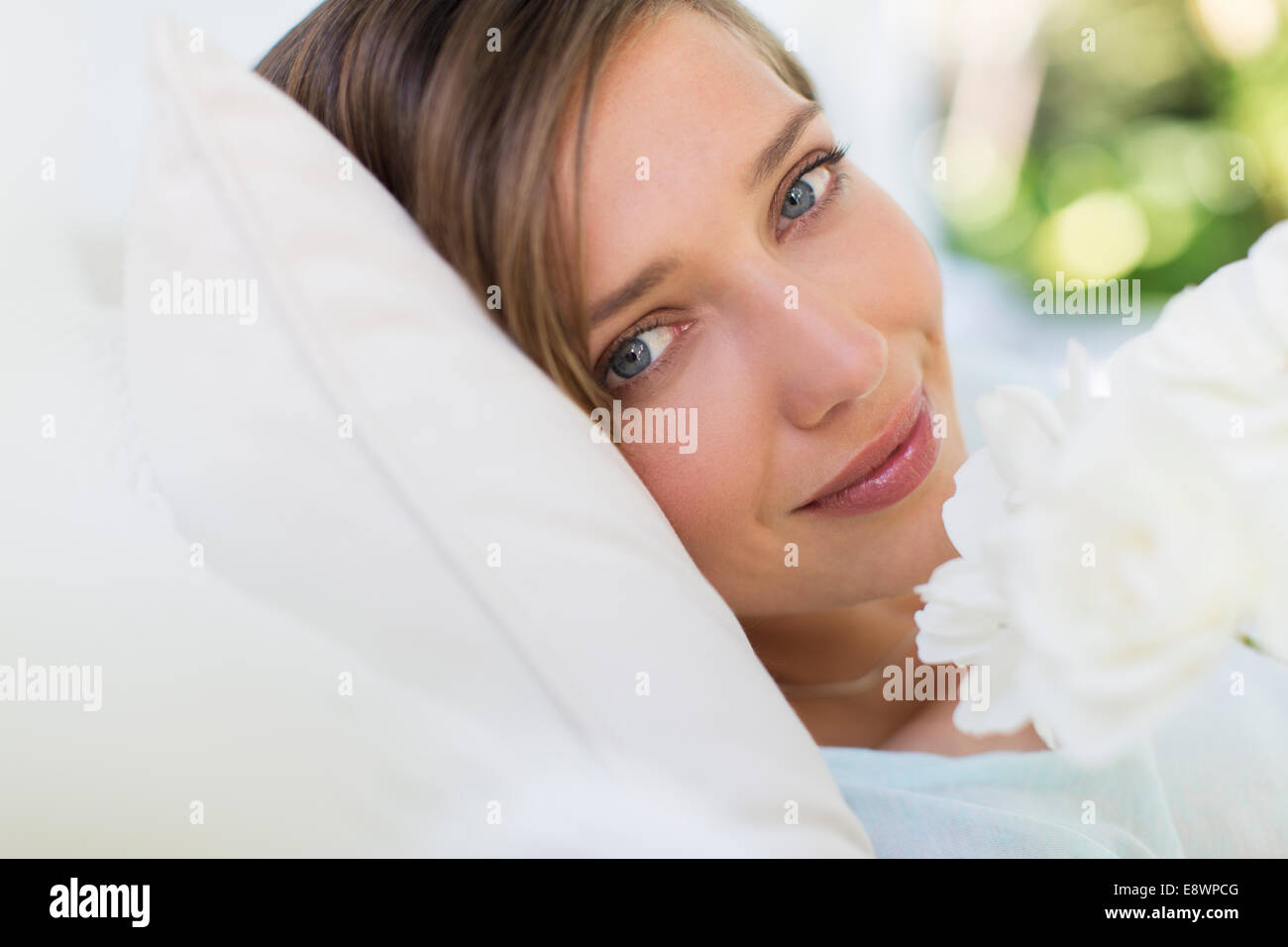 Nahaufnahme von Frau riechende Blume auf Bett Stockfoto