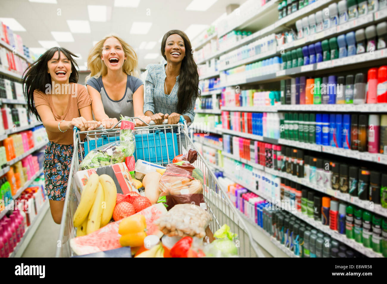 Frauen spielen mit Einkaufswagen im Supermarkt Gang Stockfoto