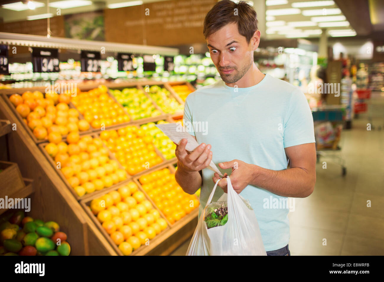 Überrascht Mann liest Eingang in Lebensmittelgeschäft Stockfoto