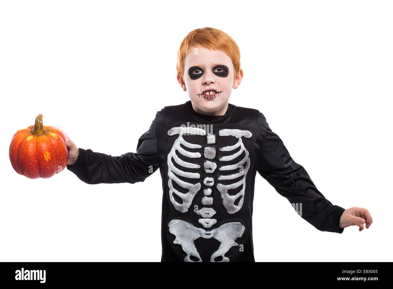 Porträt des kleinen roten Haaren jungen Halloween Skelett Kostüm trägt und hält Kürbis Stockfoto