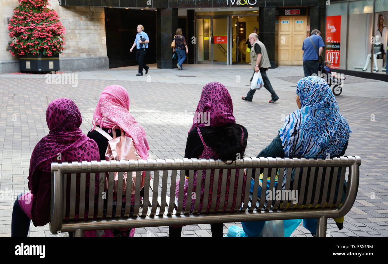 Vier muslimische Frauen auf einem Sitz, alle mit Hijab, Nottingham, England. Stockfoto