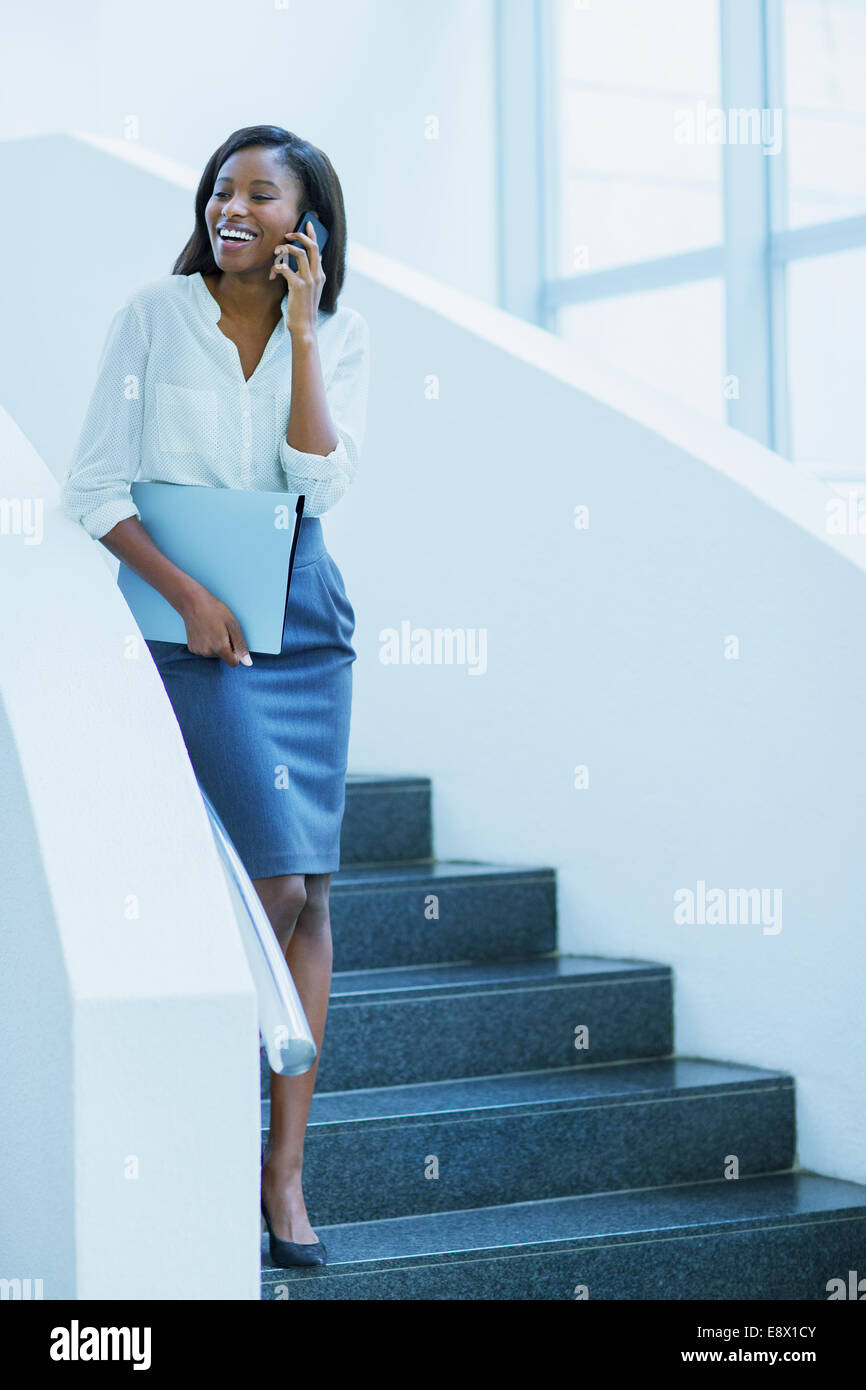 Geschäftsfrau, die zu Fuß auf Handy auf Treppe Bürogebäude Stockfoto