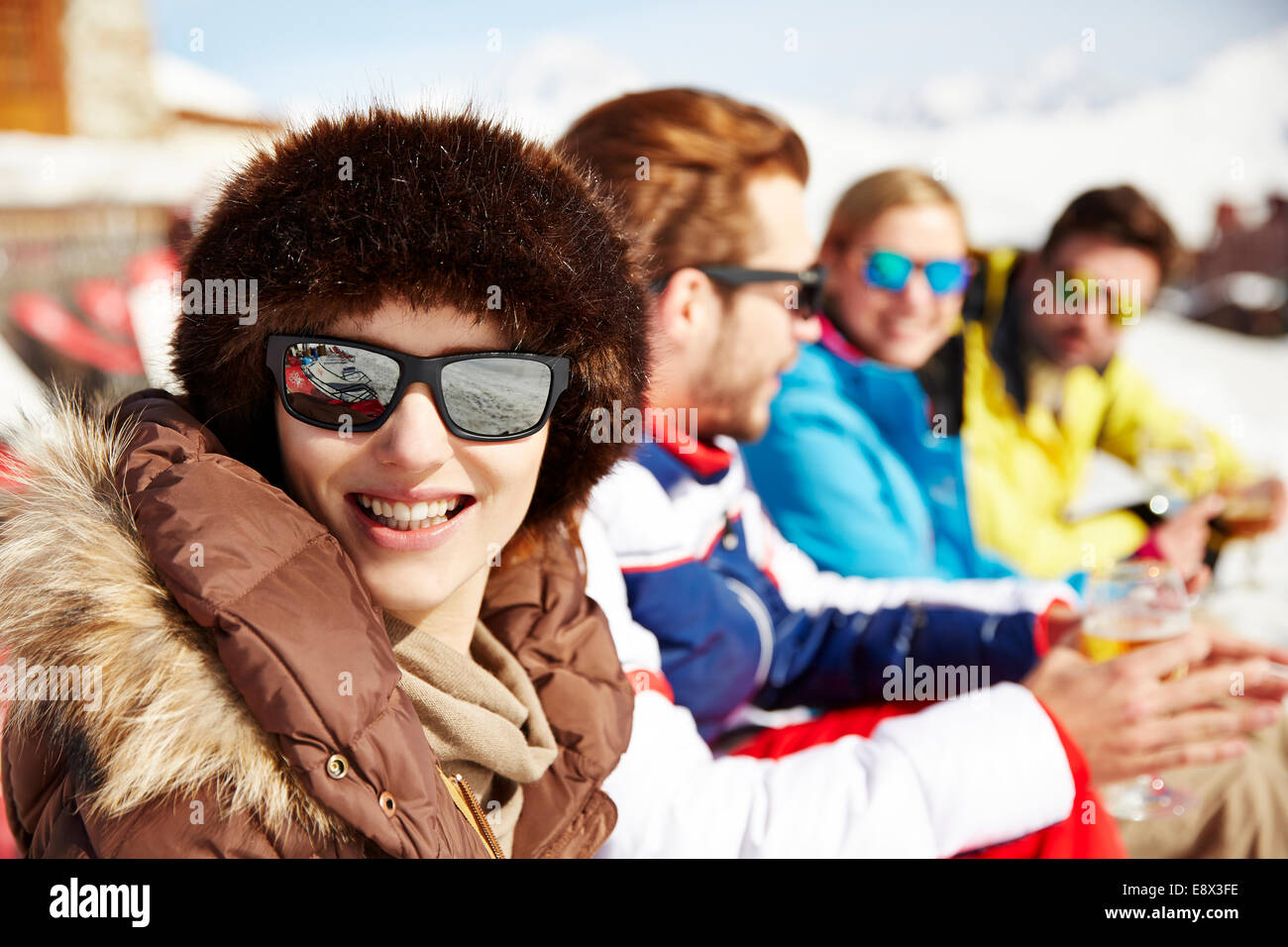 Frau sitzt mit Freunden im Schnee Stockfoto