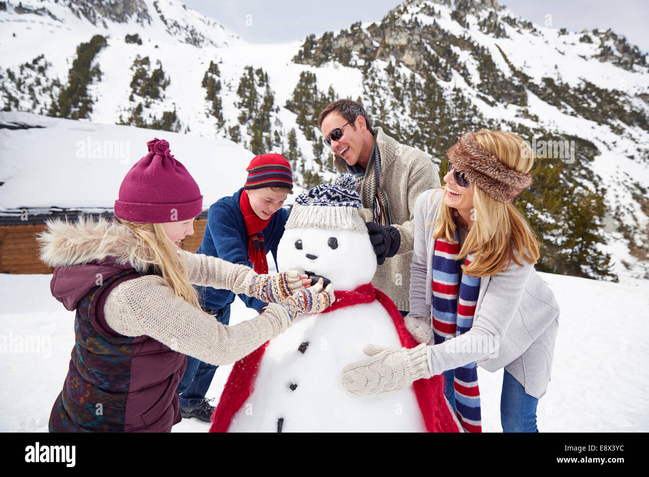 Familie gemeinsam einen Schneemann bauen Stockfoto