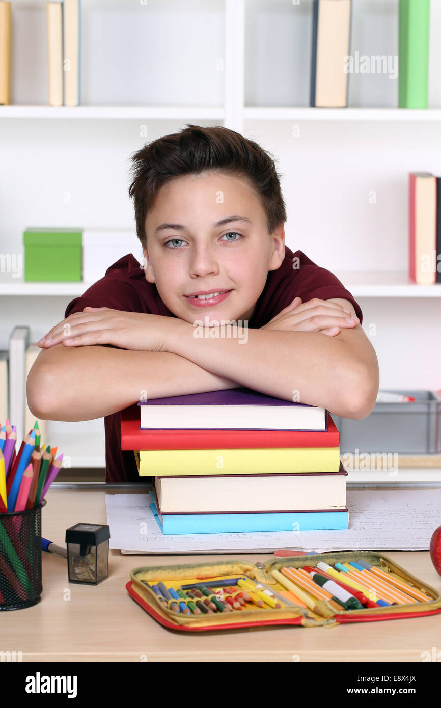 Junger Student hielt seinen Kopf auf einem Stapel Bücher während der Hausaufgaben in der Schule Stockfoto