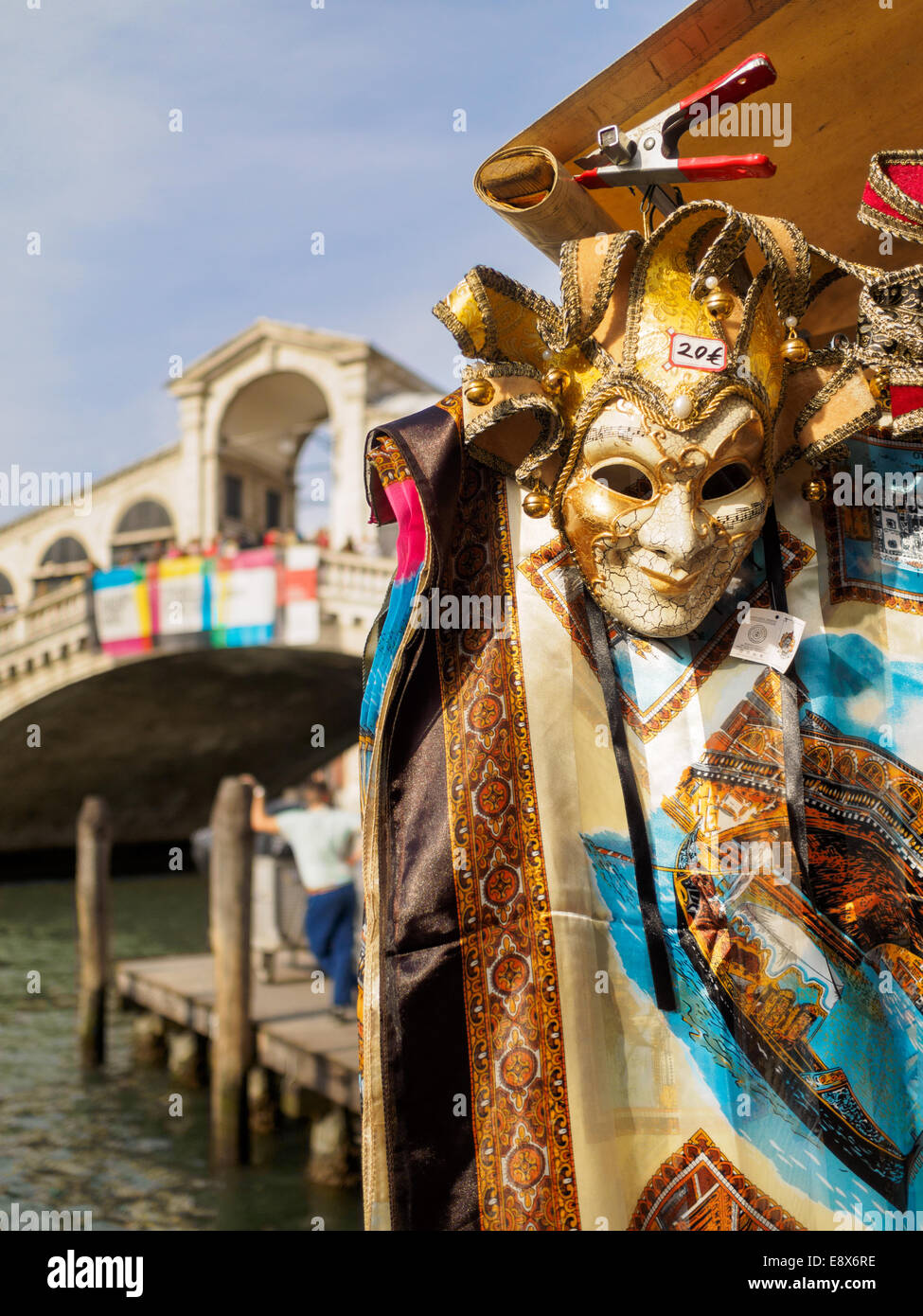 Venezianische Maske und Blatt zum Verkauf stand mit Rialto-Brücke im Hintergrund. Stockfoto