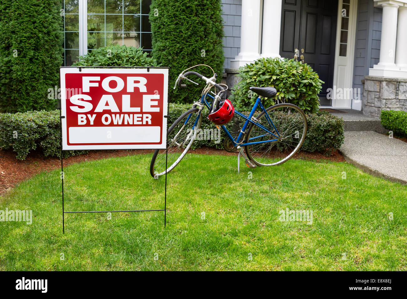 Detailansicht des Modern Suburban Home mit für Real Estate Verkaufsschild vor Hof und Fahrrad und Haus im Hintergrund Stockfoto