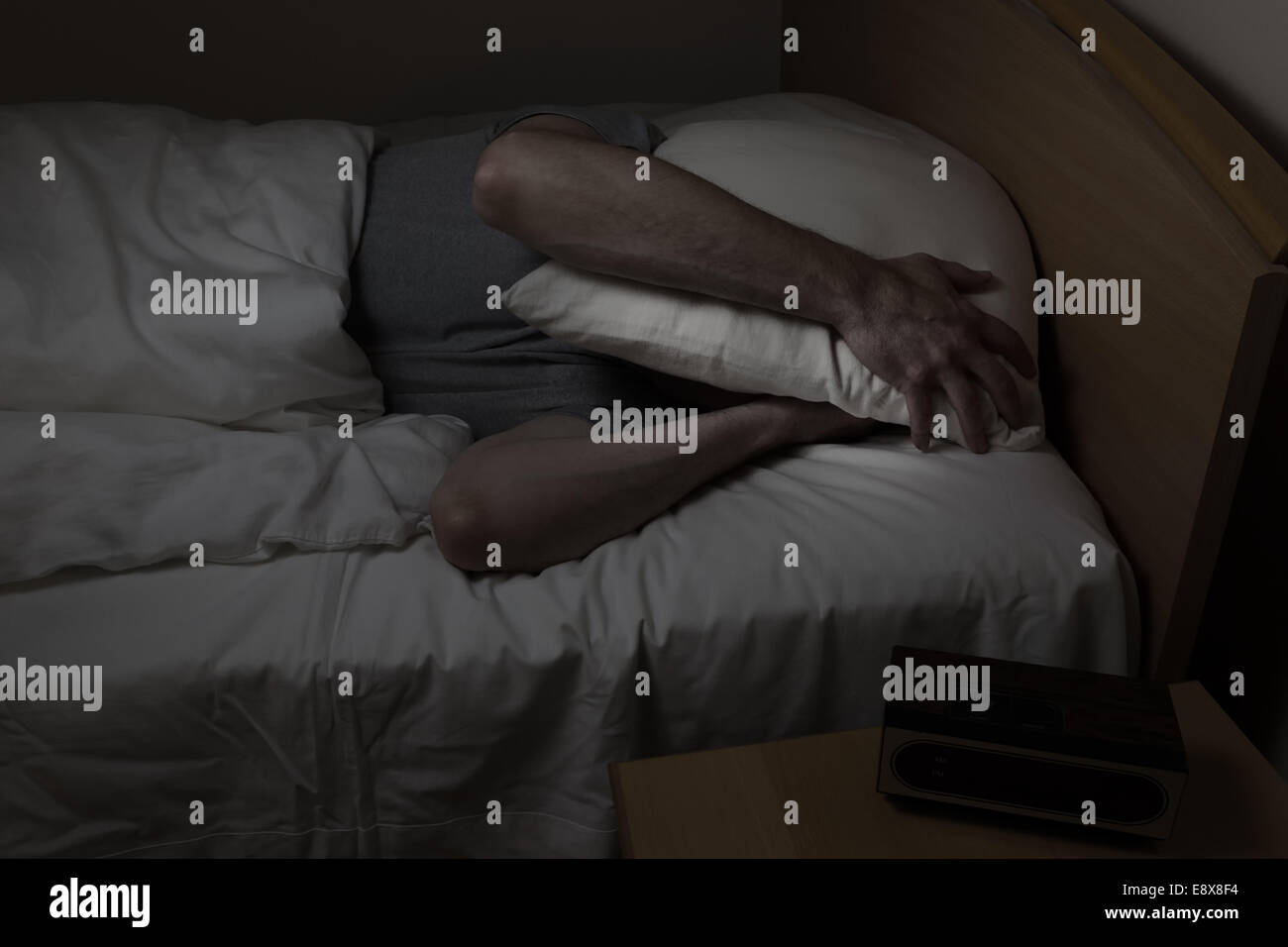 Reifer Mann kann nicht mit Kissen bedeckte ganzes Gesicht unter Schlaflosigkeit nachts schlafen. Stockfoto