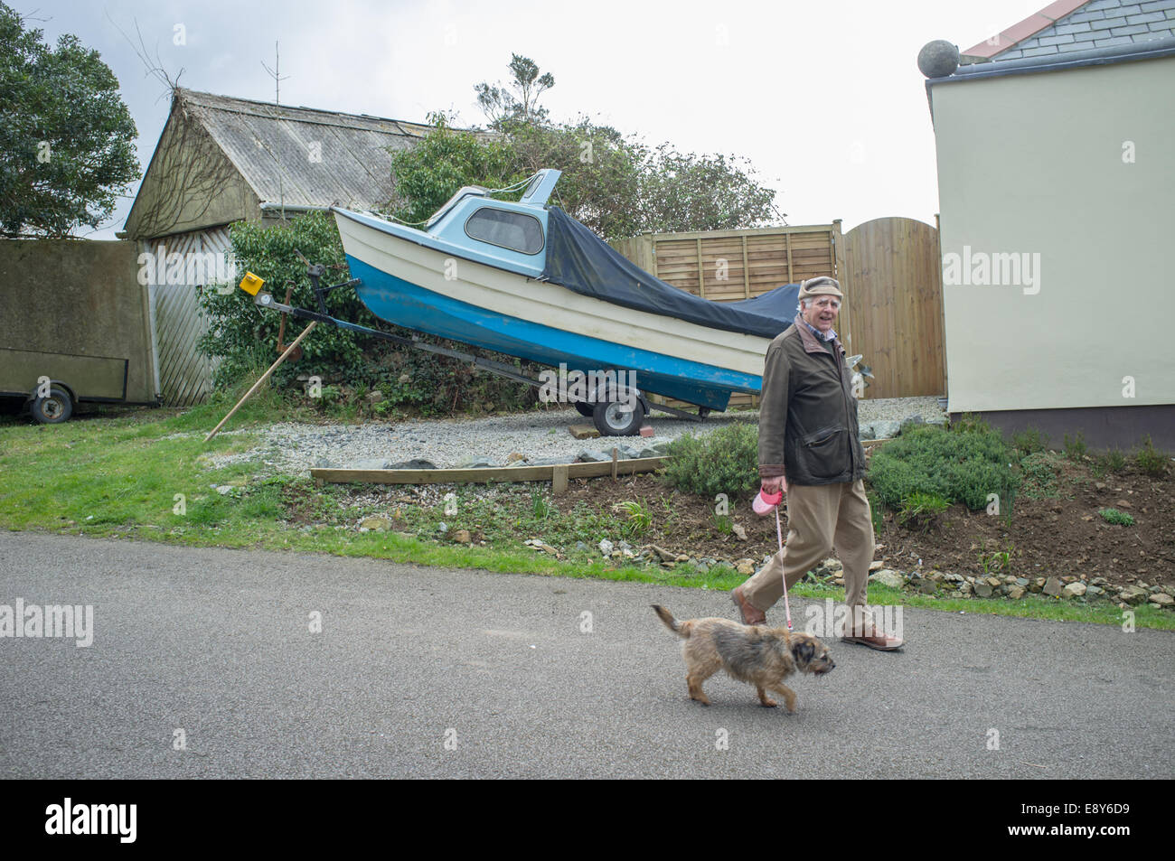 Ein pensionierter Mann geht seinen Hund in Flushing Cornwall Stockfoto