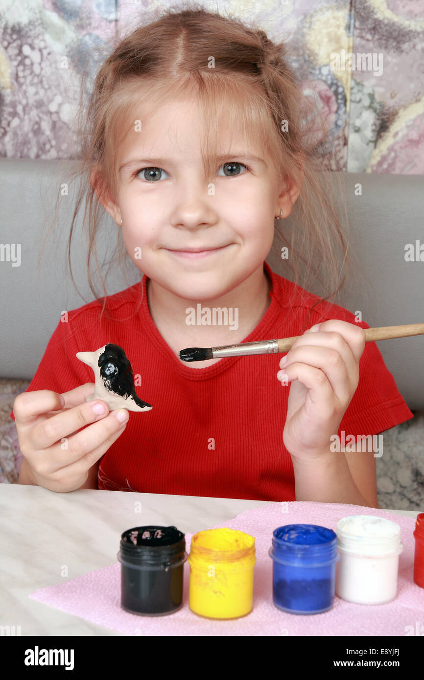 Begeistert kleine Mädchen malt eine Tonfigur Stockfoto