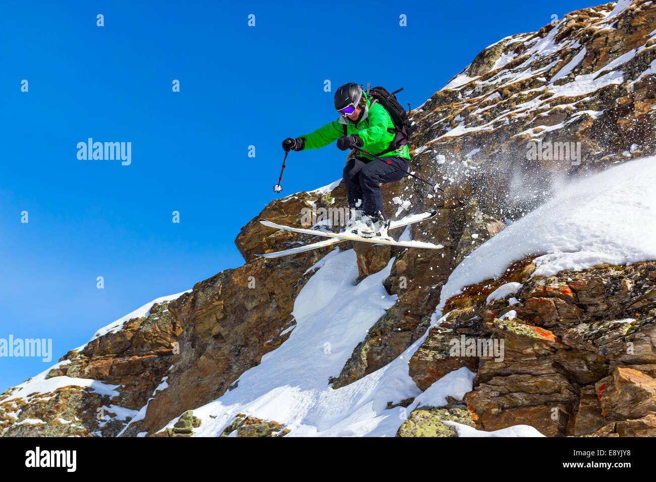 Frau Skifahrer Sprung von einer Klippe in den Bergen an einem sonnigen Tag Stockfoto