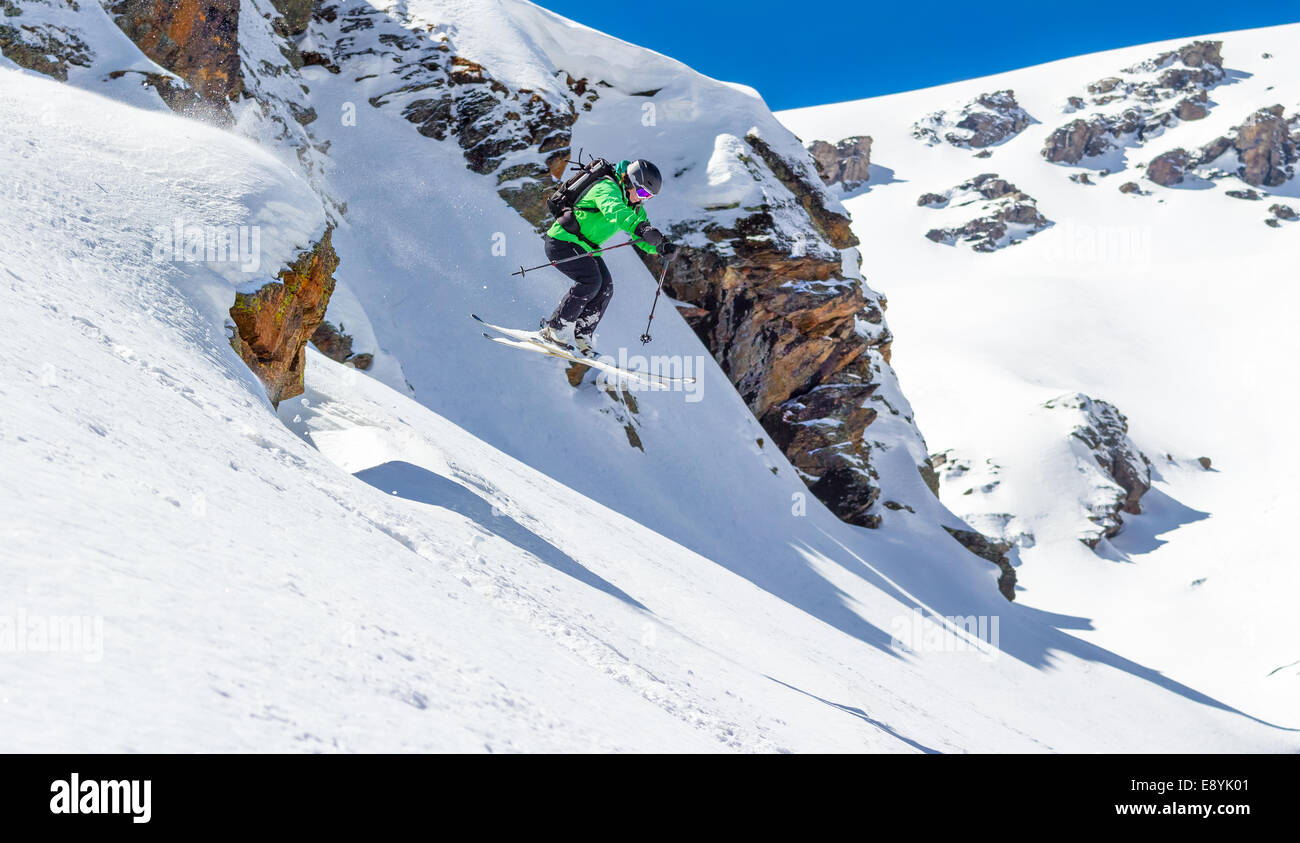 Frau Skifahrer Sprung von einer Klippe in den Bergen an einem sonnigen Tag Stockfoto