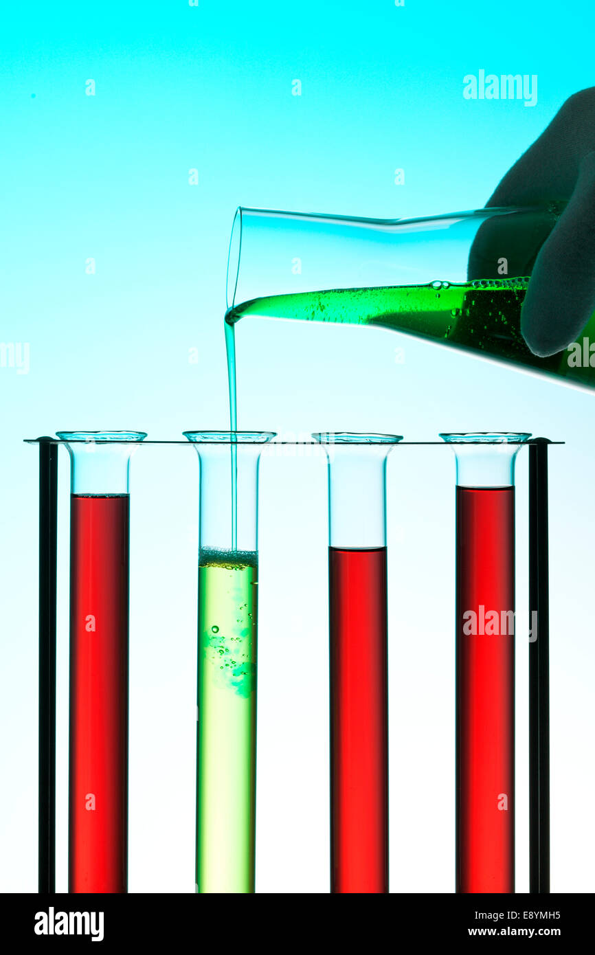 Chemisches Labor Konzept - Gießen grünen Flüssigkeit aus Erlenmeier Flasche in Reagenzglas in einem rack Stockfoto