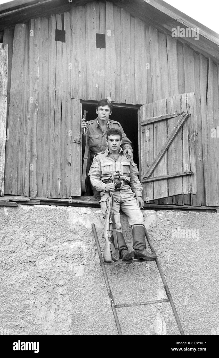 Zwei Soldaten mit Gewehren auf dem Dachboden eines alten Hauses posieren. Film scannen. Große Körner Stockfoto