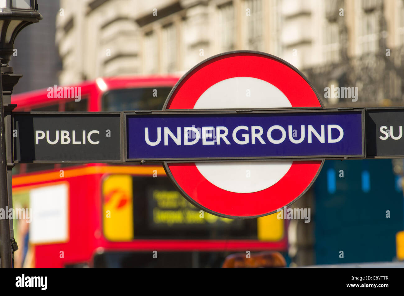 Red London Bus vorbei hinter London Underground Zeichen, London, England Stockfoto