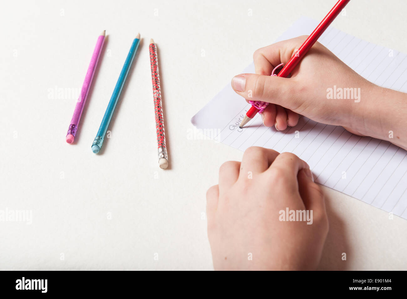Ein Kind schreibt auf ein Blatt Papier mit einem Bleistift Stockfoto
