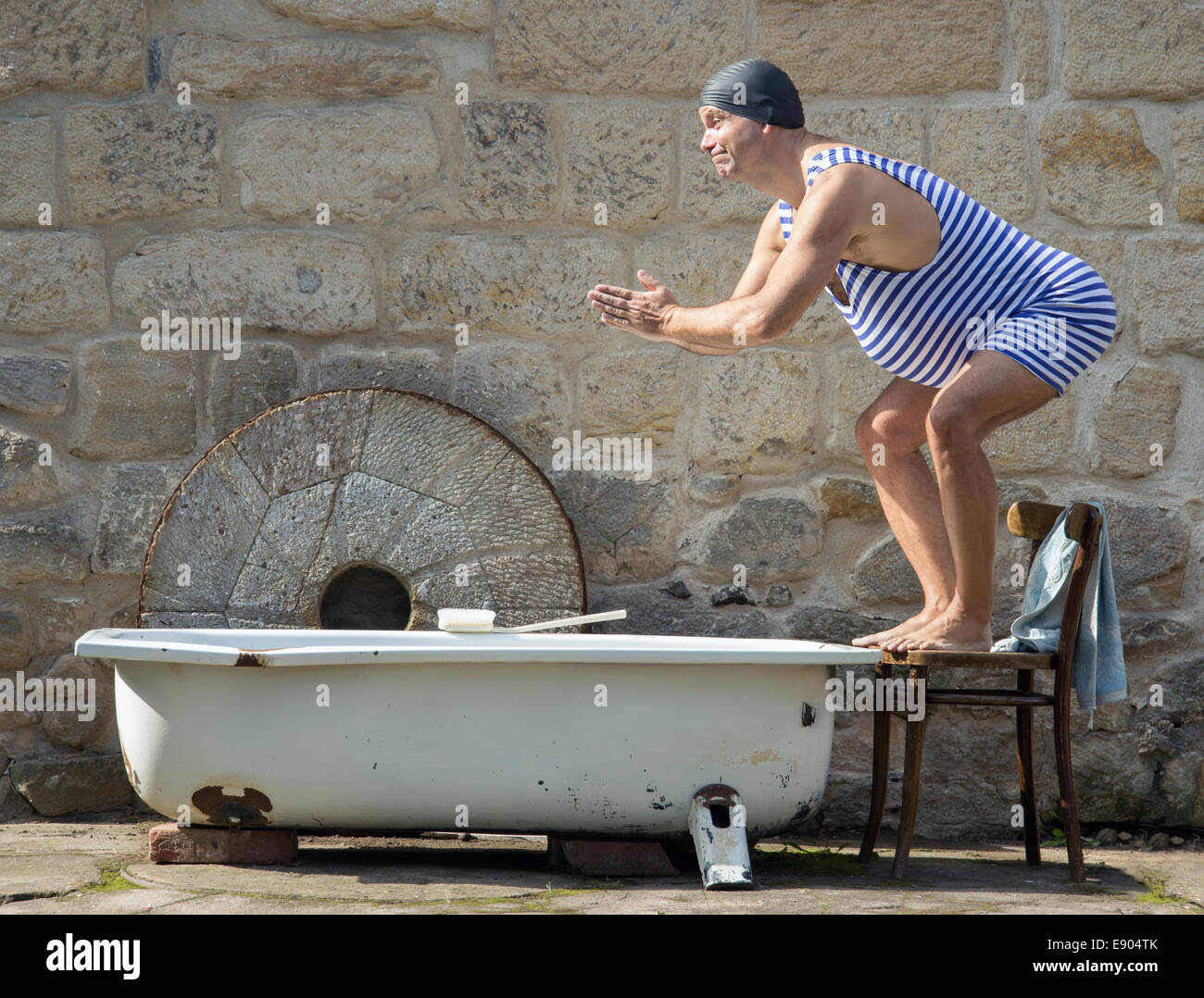 Mann in Retro-Badeanzug springt an der Badewanne im freien Stockfoto