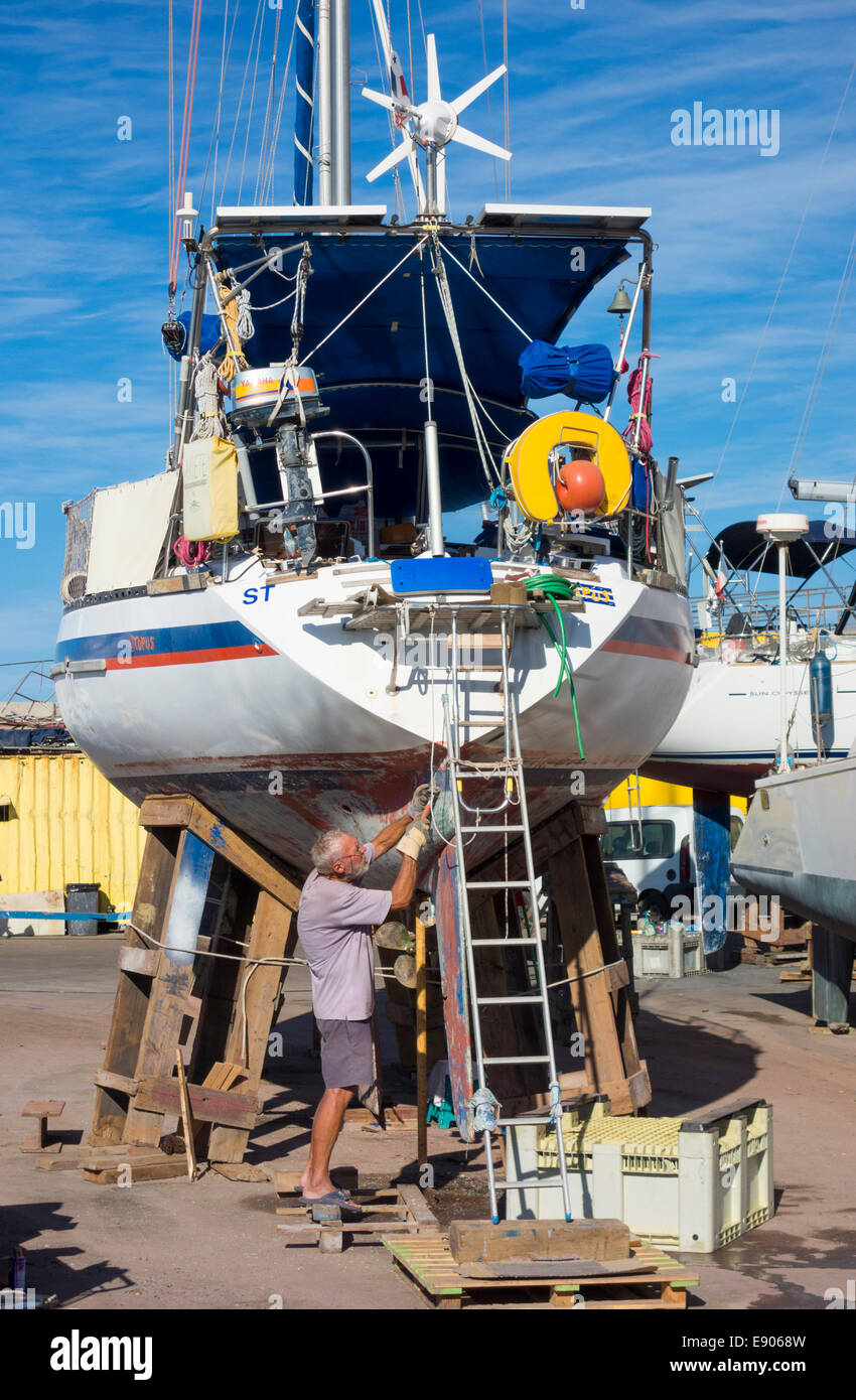 Schaben Farbe der Yacht Rumpf in Marina Reparaturwerft. Puerto de Mogan, Gran Canaria, Kanarische Inseln Stockfoto