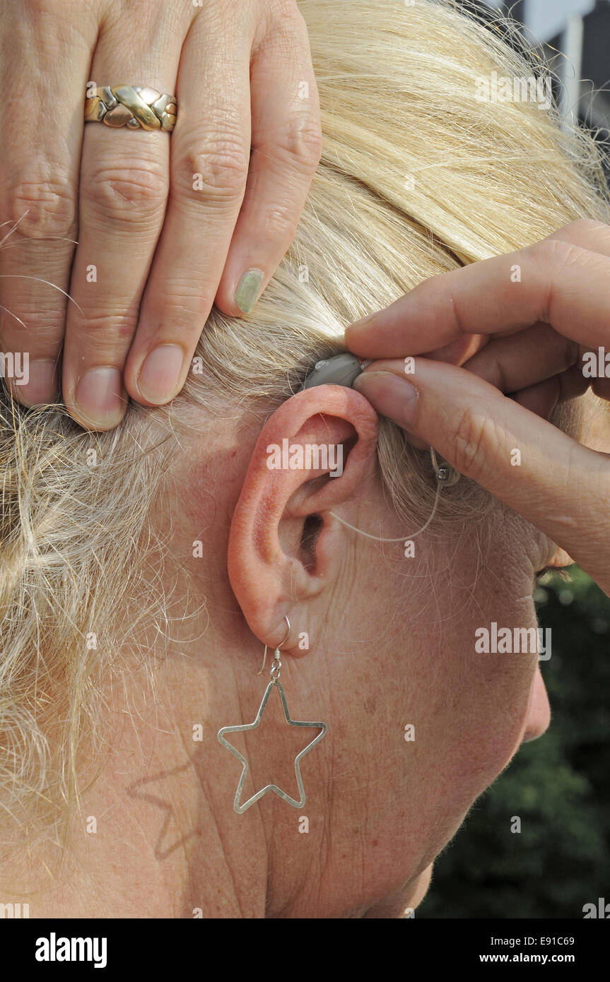 Moderne kleine Hörgerät hinter dem Ohr einer Frau Stockfoto
