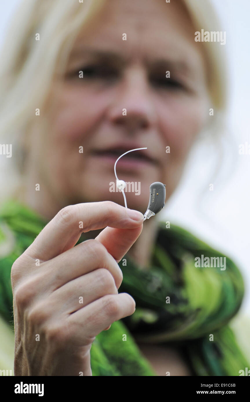 Moderne kleine Hörgerät in die Hand einer Frau Stockfoto