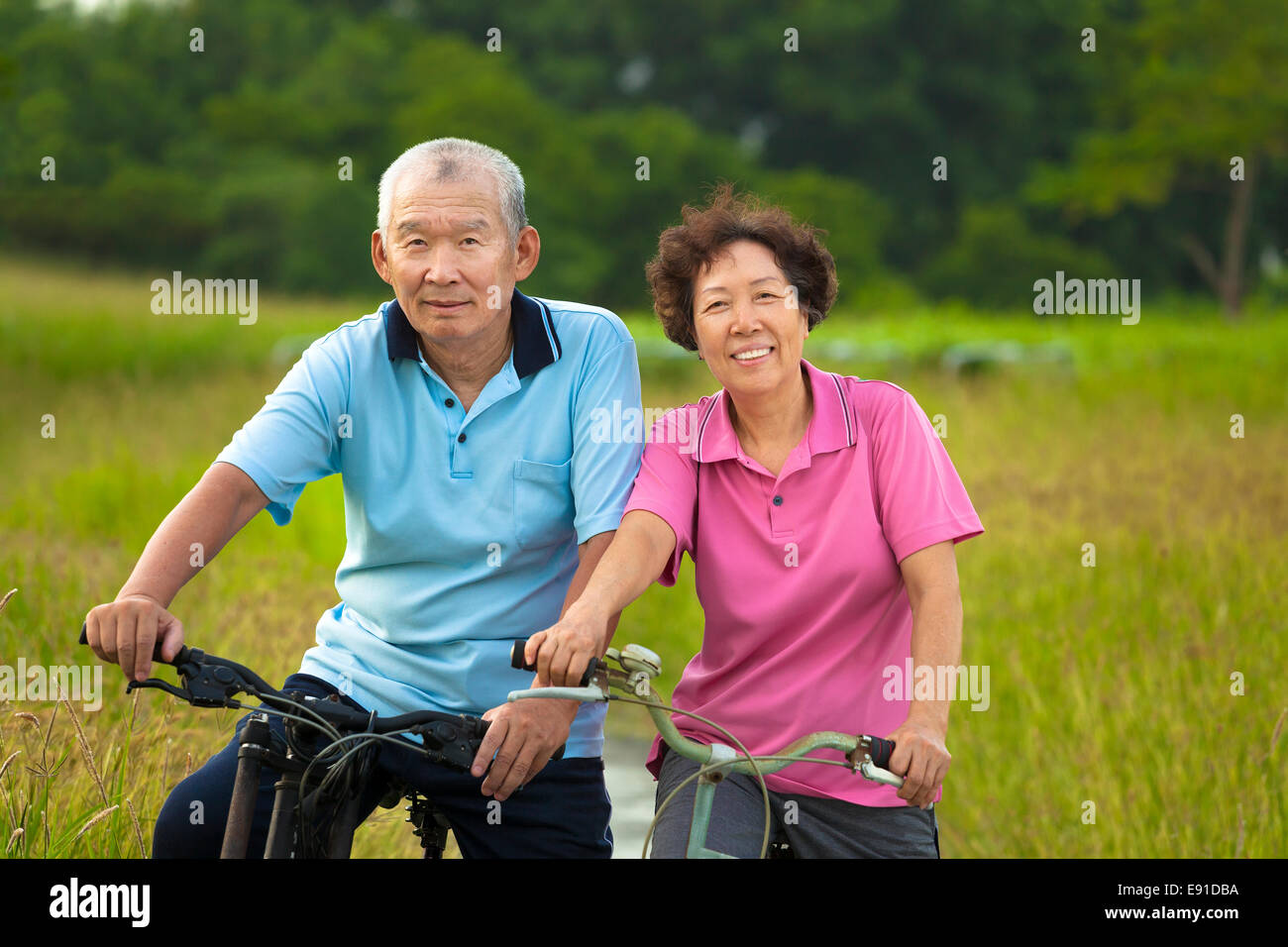 Glücklich asiatischen Senioren paar Radfahren im Park. Rente und Gesundheit-Konzept Stockfoto