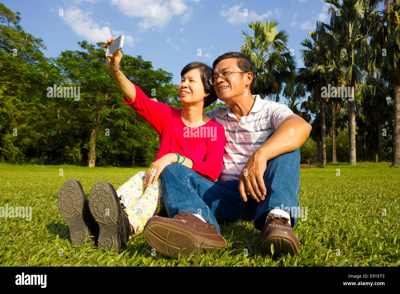 Asiatische Senior paar sitzen auf Grünland und unter Bild selbst außerhalb Stockfoto