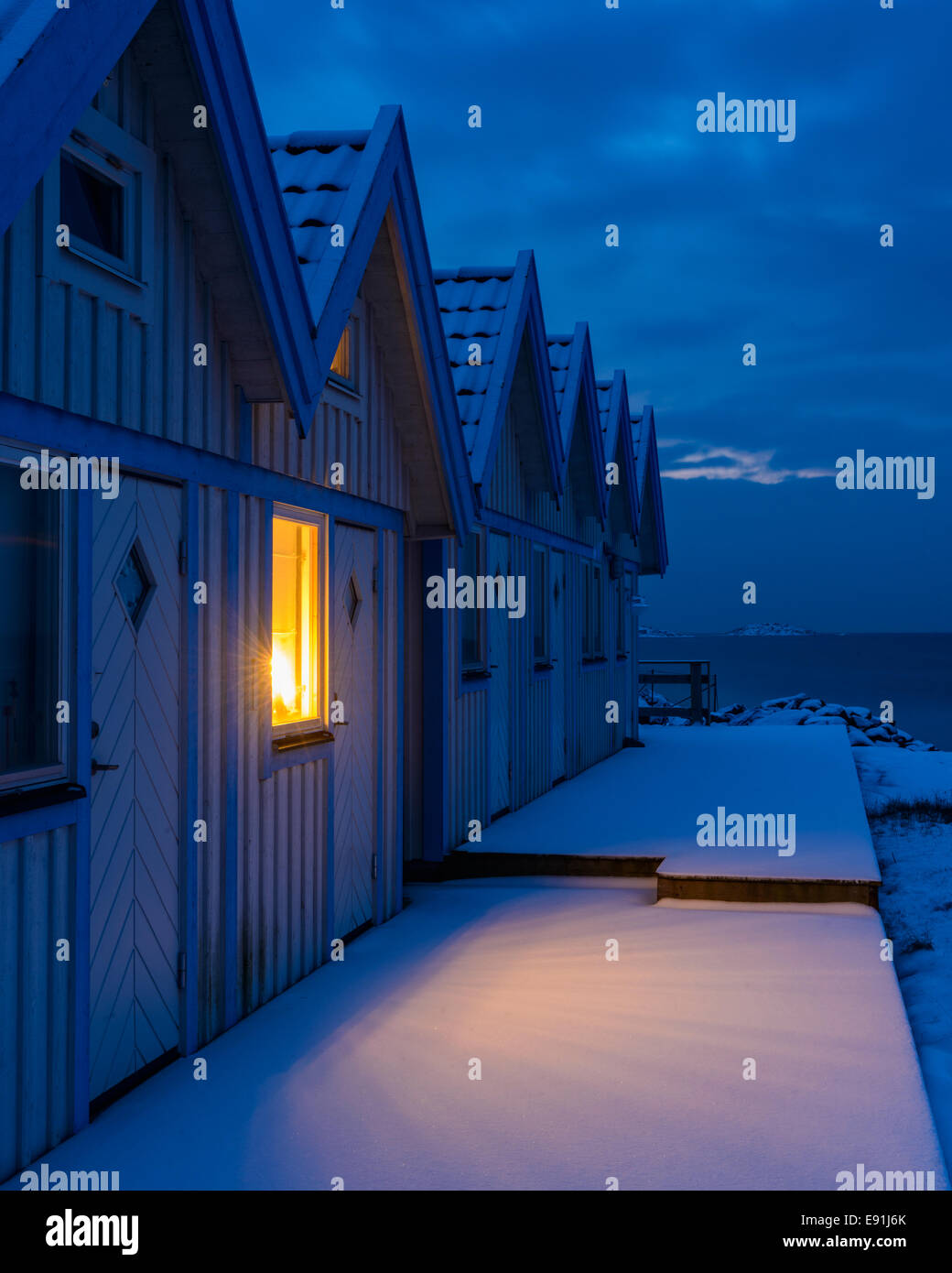 Beleuchtete Fenster in einer Reihe von Strandhütten in der Nacht Stockfoto