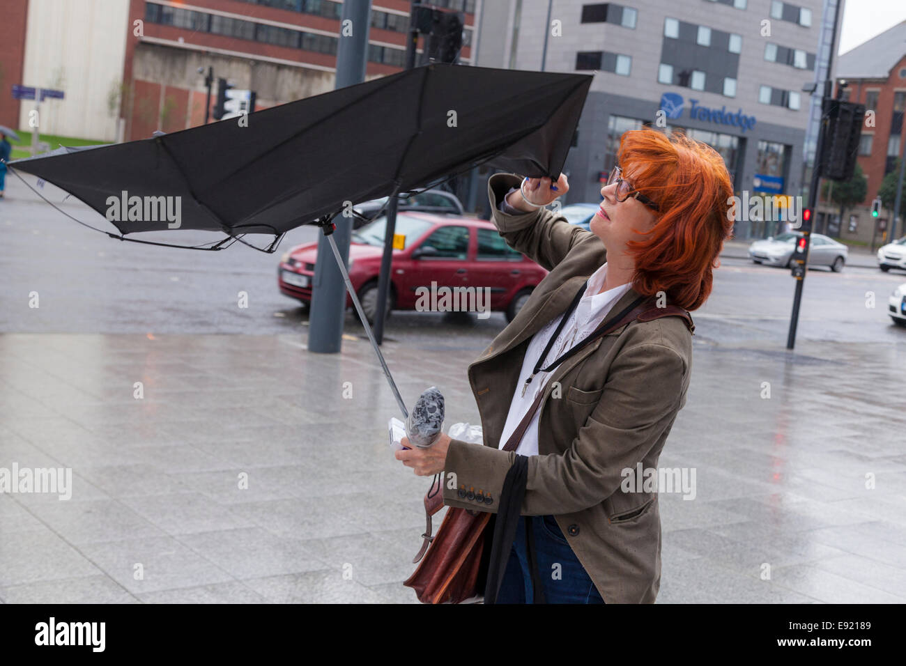 Einen Regenschirm an einem windigen Tag. Eine Frau mit einem Regenschirm in der vom Wind ausgeblasen, Liverpool, England, UK Stockfoto