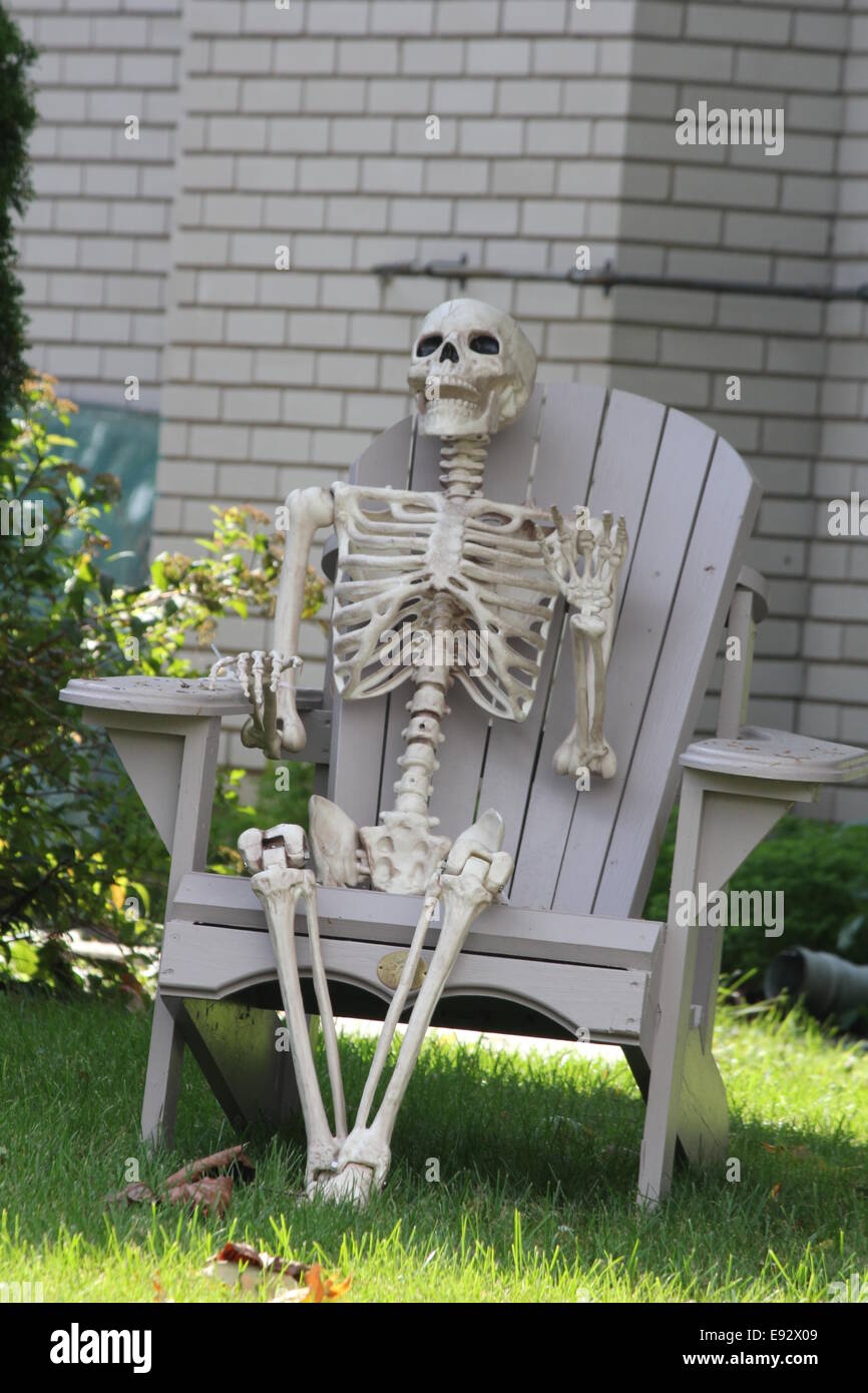 Kunststoff, dekorativ, Nachahmung von einem menschlichen Skelett, sitzt auf  einem Hof-Stuhl, in Vorbereitung für Halloween Stockfotografie - Alamy