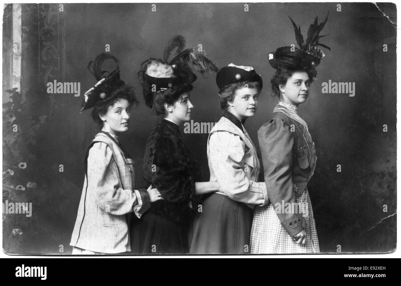 Vier modische Frauen in gefiederten Hüte stehen in Reihe mit Händen berühren Taillen, Porträt, um 1915 Stockfoto